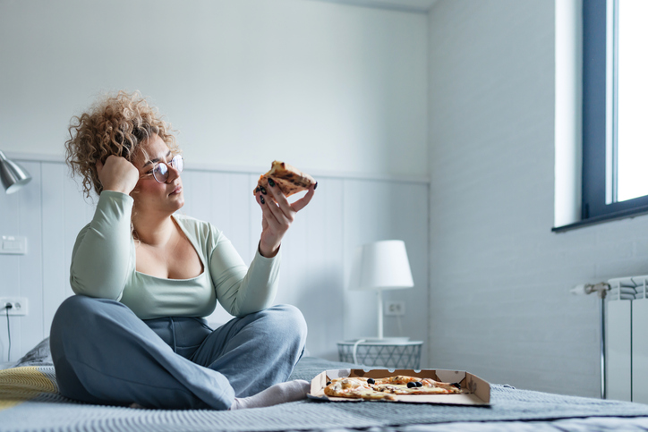 Vrouw eet met tegenzin pizza