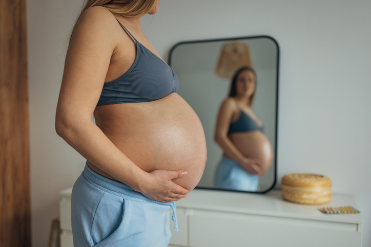 Zwangere vrouw kijkt in spiegel