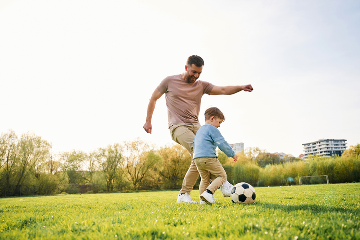 man en kind spelen potje voetbal