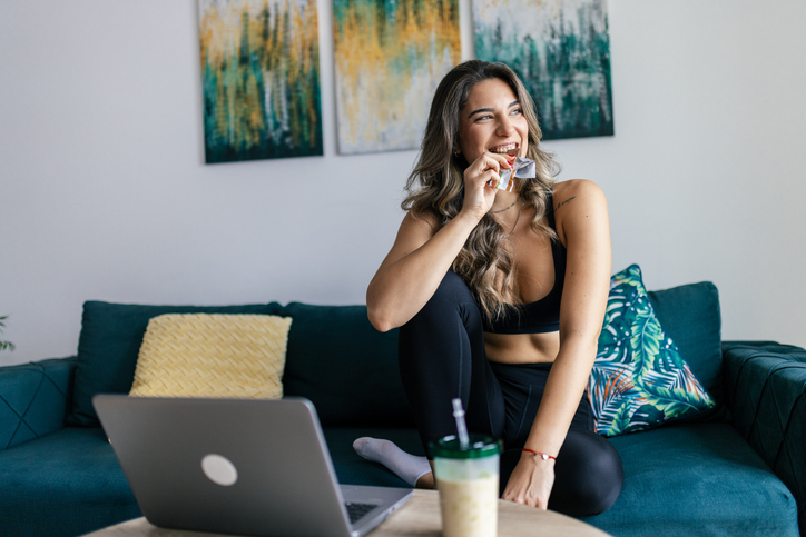 Vrouw eet proteïne reep op bank