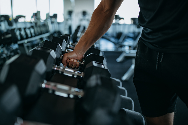 Man pakt dumbbell uit dumbbell rek