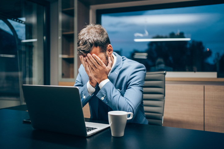 Man zit achter laptop met handen in gezicht