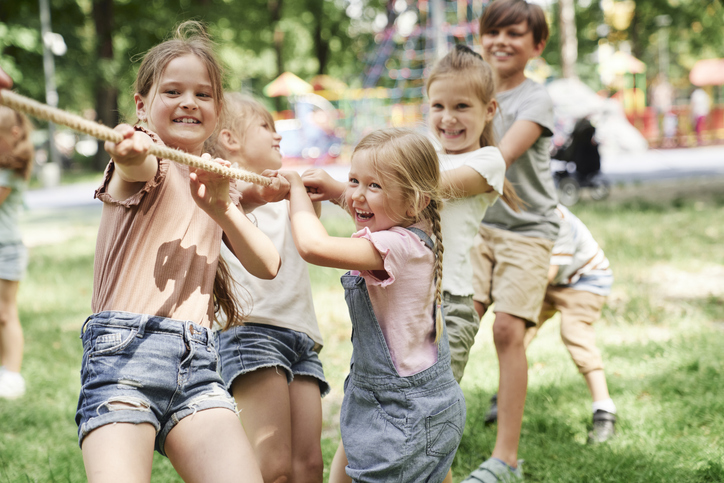Groep kinderen zijn aan het touw trekken en lachen erbij
